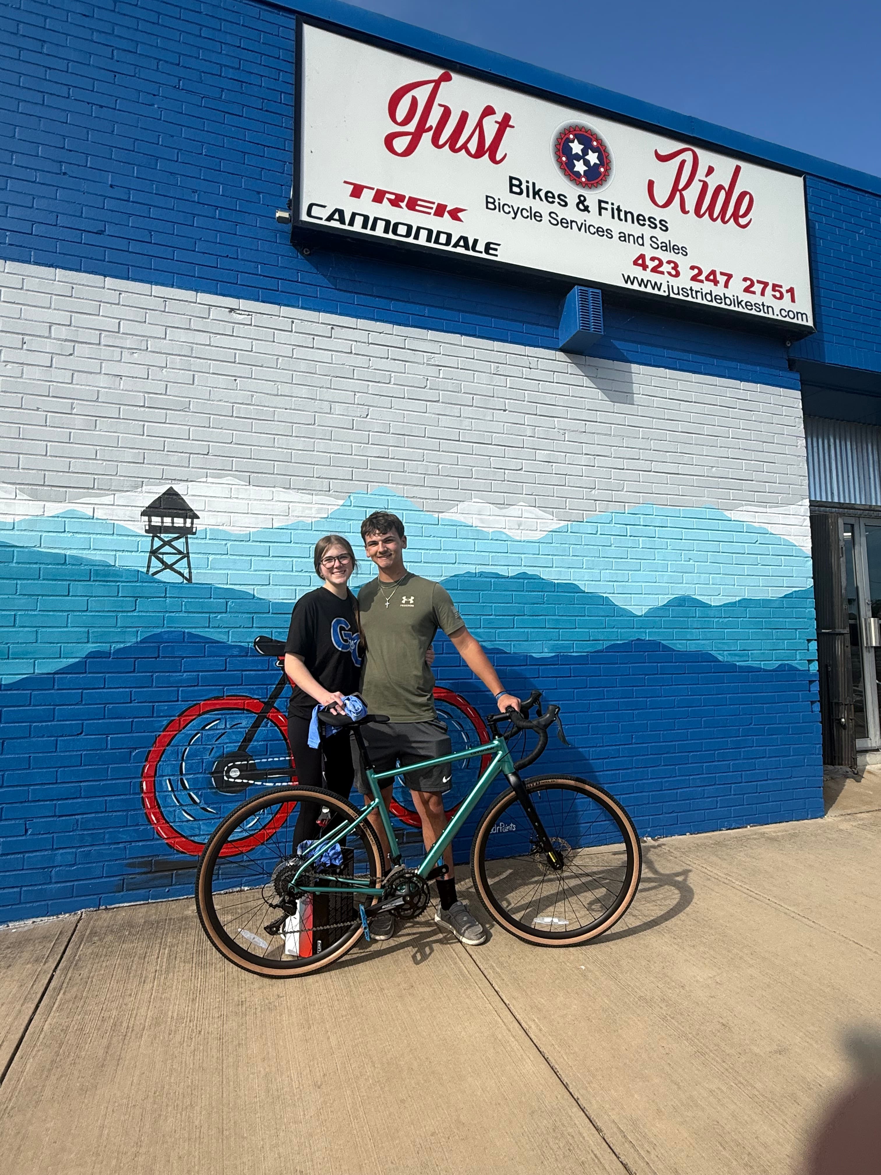A Just Ride customer with their new bike outside the shop