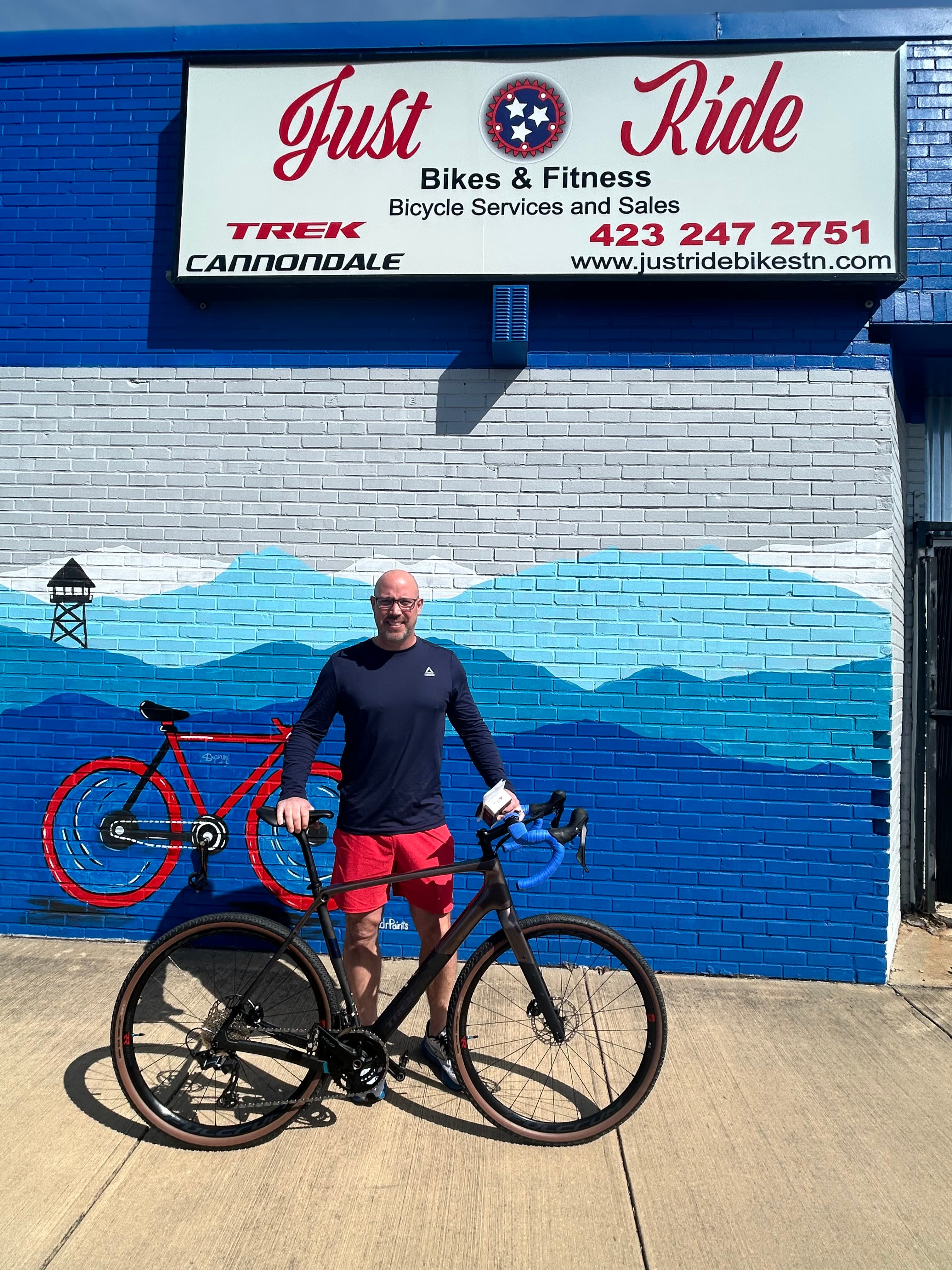A Just Ride customer with their new bike outside the shop
